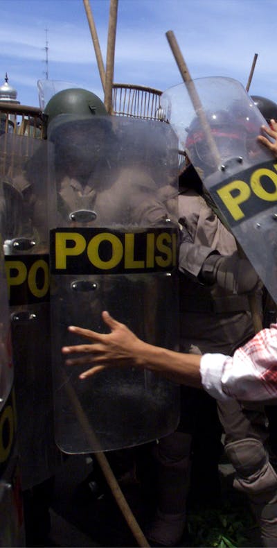 Een student in Atjeh in Indonesië probeert een agent van de oproerpolitie weg te duwen