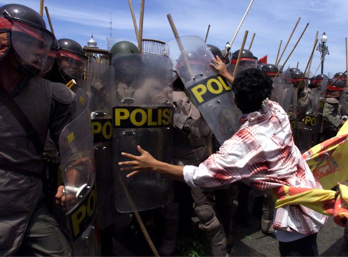 Een student in Atjeh in Indonesië probeert een agent van de oproerpolitie weg te duwen