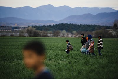 Vluchtelingen lopen door een veld in de buurt van een provisorisch vluchtelingenkamp nabij de Grieks-Macedonische grens