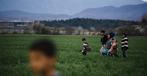 Vluchtelingen lopen door een veld in de buurt van een provisorisch vluchtelingenkamp nabij de Grieks-Macedonische grens Vluchtelingen lopen door een veld in de buurt van een provisorisch vluchtelingenkamp nabij de Grieks-Macedonische grens