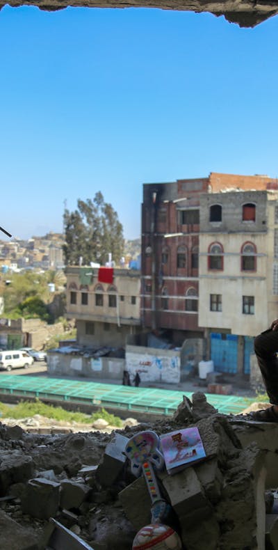 Een jongen uit de Jemenitische stad Taez staat in een gebouw dat gedeeltelijk verwoest is door een mortieraanval (3 februari 2016). Een coalitie onder aanvoering van Saudi-Arabië voert daar een oorlog tegen de Houthi's.