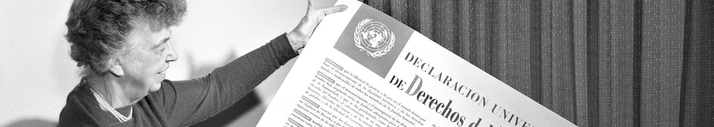 Eleanor Roosevelt bekijkt een poster met daarop de UVRM in het Spaans