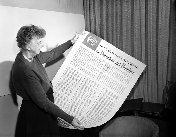 Eleanor Roosevelt bekijkt een poster met daarop de UVRM in het Spaans