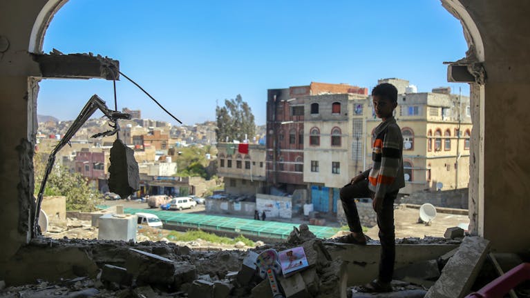 Een jongen bekijkt de schade na een mortieraanval op de Jemenitische stad Taiz in februari 2016. Alle partijen in het conflict, waaronder een door Saudi-Arabië geleide coalitie, hebben zich schuldig gemaakt aan ernstige schendingen van internationale humanitaire wetten.