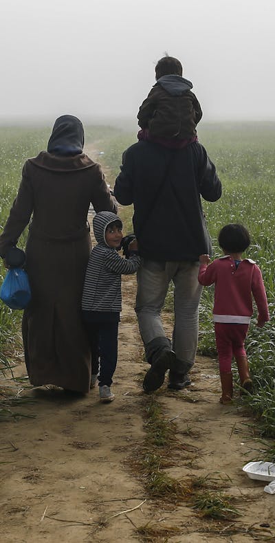 Een gezin loopt door de velden in de buurt van een provisorisch opvangkamp bij Idomeni, Griekenland.