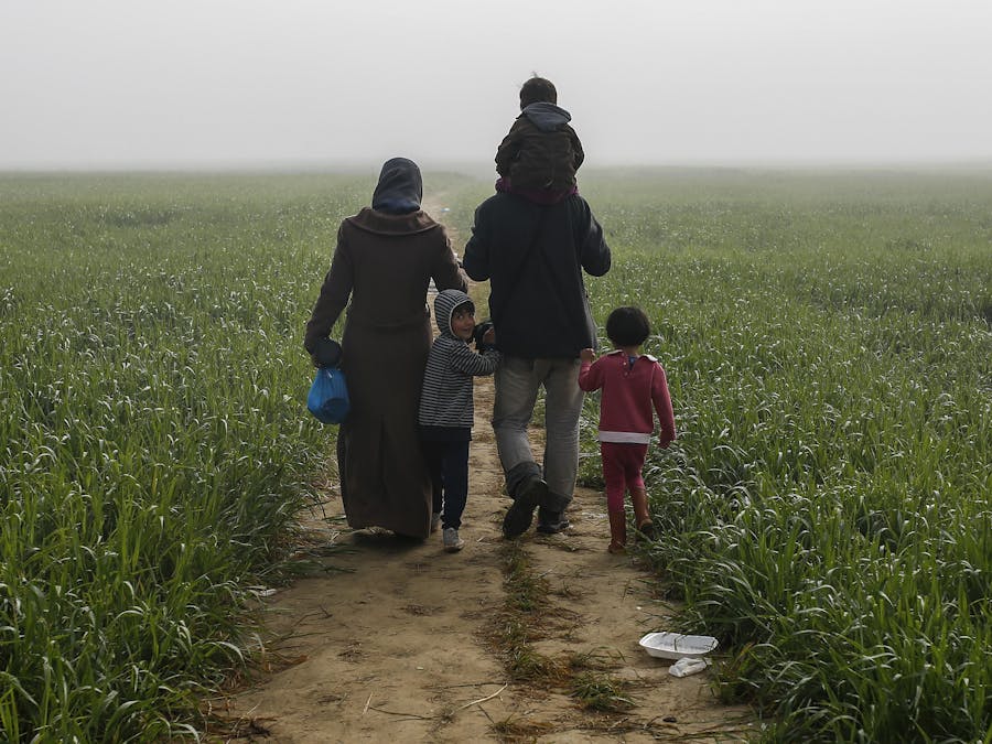Een gezin loopt door de velden in de buurt van een provisorisch opvangkamp bij Idomeni, Griekenland.