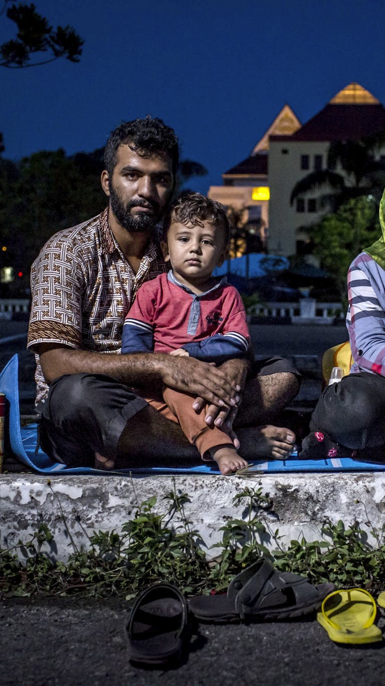 De Afghaanse asielzoeker Hasan Remezonei en zijn gezin op een parkeerplaats in de Indonesische stad Batam. Het aantal asielzoekers in Indonesië groeit; ze komen er vast te zitten, terwijl ze het liefst asiel zouden krijgen in landen als Nieuw-Zeeland en Australië.