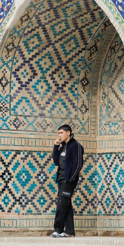 Telefonerende jongen bij een moskee in Oezbekistan.