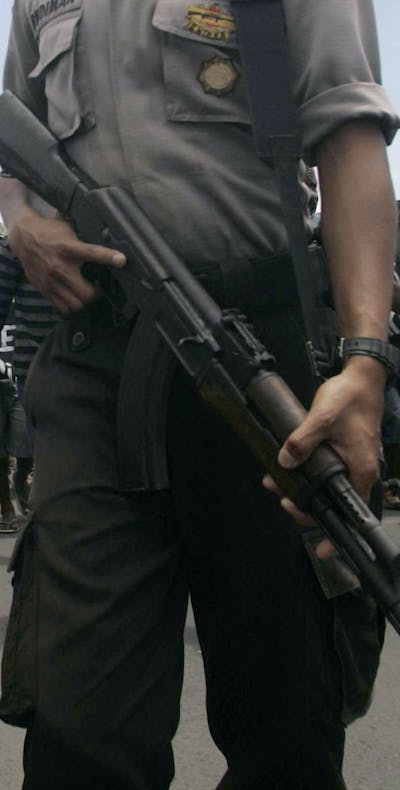 Een gewapende politieman houdt toezicht op een menigte demonstrerende Papoea’s die de weg naar een vliegveld in de Indonesische provincie Papoea blokkeren. (2009).