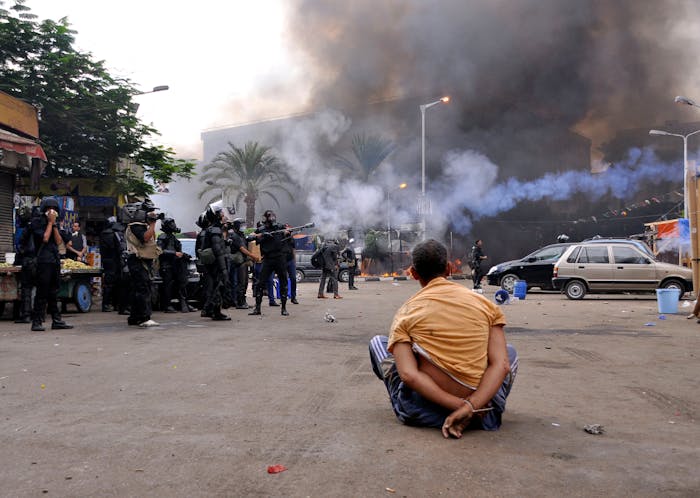 Een gehandboeide demonstrant op het Al-Nahdaplein in Caïro op 14 augustus 2013. Op de achtergrond gewapende veiligheidstroepen, die door Frankrijk geleverde wapens inzetten.