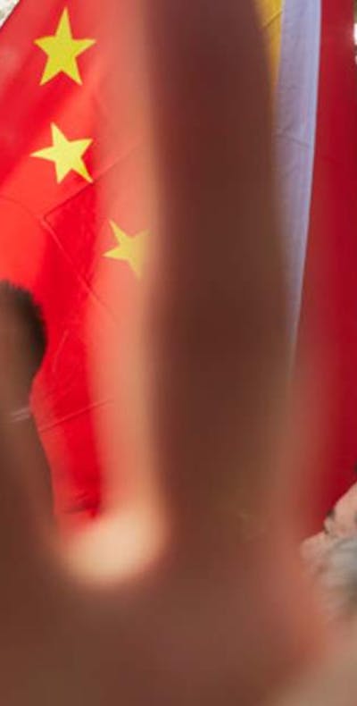 Chinese man probeert met zijn hand een foto te voorkomen van een demonstratie tegen de Chinese repressie