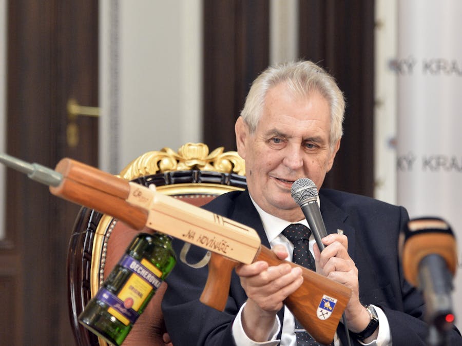 De Tsjechische president Milos Zeman houdt een namaakgeweer omhoog met de tekst “voor journalisten”.