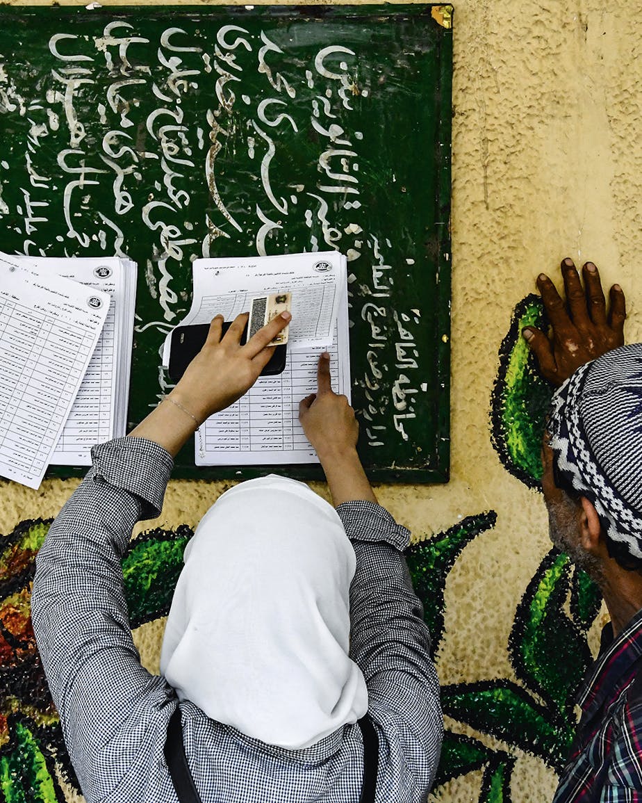 Egyptenaren zoeken hun naam op de lijst om te kunnen stemmen tijdens het referendum afgelopen april