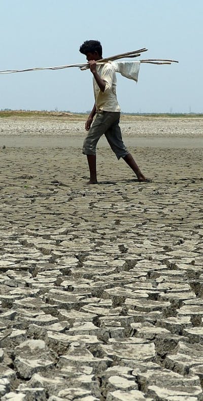 Een man loopt in een uitgedroogde rivierbedding in India, 2017