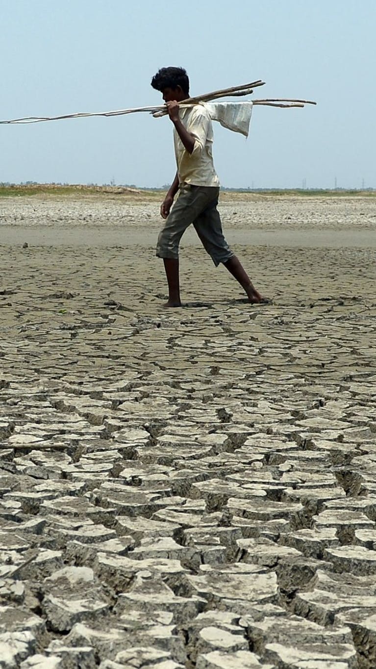 Een man loopt in een uitgedroogde rivierbedding in India, 2017