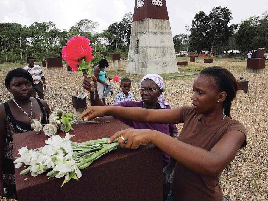 Marrons leggen bloemen bij een monument ter nagedachtenis aan het bloedbad in Moiwana.