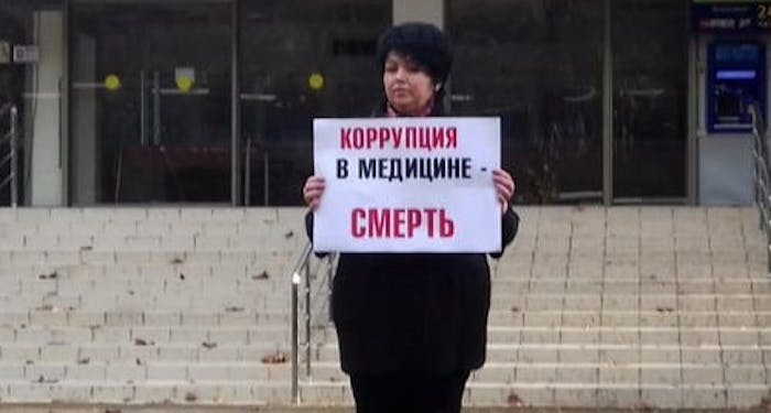 De Russische arts Yulia Volkova kan een fikse boete krijgen omdat ze kritiek uitte op de corona-aanpak in haar land. Op het bord staat: corruptie in geneeskunde = de dood.
