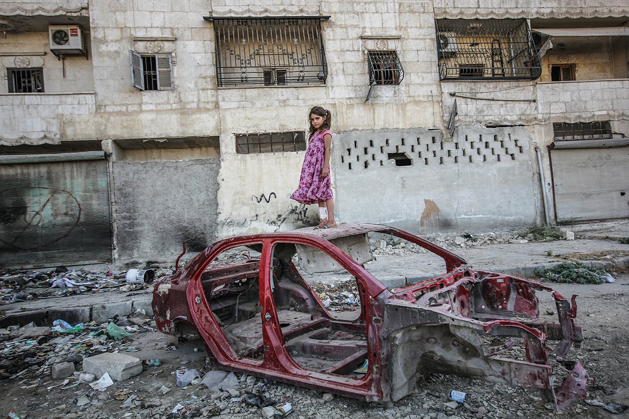 Een meisje op een autowrak in de wijk Al-Mashhad in Aleppo, september 2015