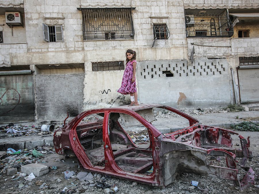 Een meisje op een autowrak in de wijk Al-Mashhad in Aleppo, september 2015