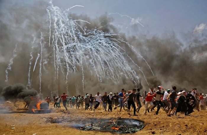 Palestijnen vluchten voor traangasgranaten tijdens botsingen met Israëlische veiligheidstroepen aan de grens met Israël en de Gazastrook, mei 2018.