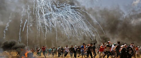 Palestijnen vluchten voor traangasgranaten tijdens botsingen met Israëlische veiligheidstroepen aan de grens met Israël en de Gazastrook, mei 2018.