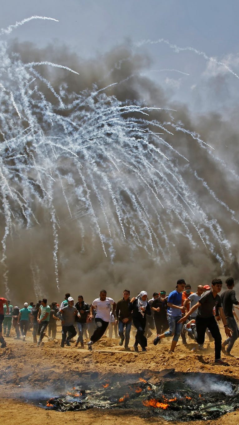 Palestijnen vluchten voor traangasgranaten tijdens botsingen met Israëlische veiligheidstroepen aan de grens met Israël en de Gazastrook, mei 2018.