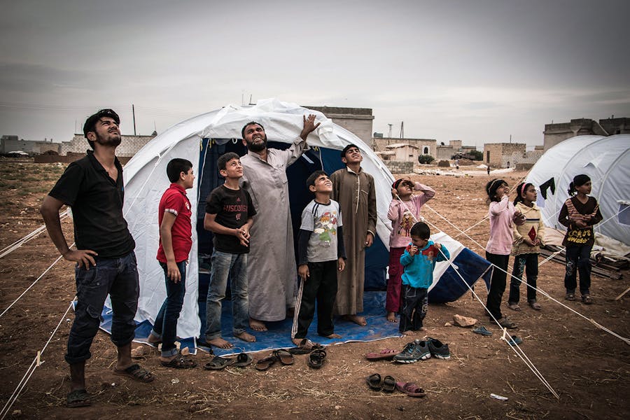 Syriërs kijken eind oktober naar een Russisch gevechtsvliegtuig boven een vluchtelingenkamp ten zuiden van Aleppo.