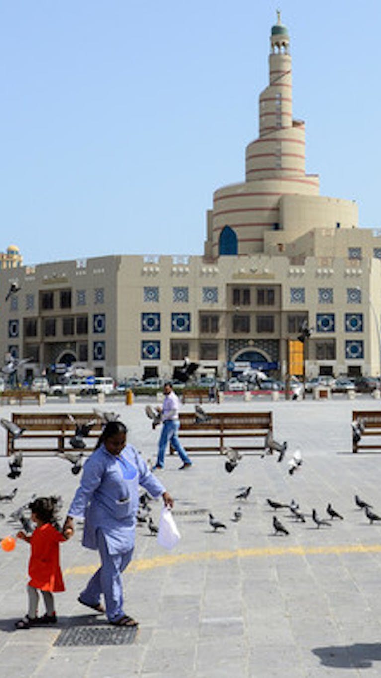 Een huishoudelijke hulp begeleidt in kind in Doha, Qatar. Veel huishoudelijk personeel wordt in Qatar uitgebuit.