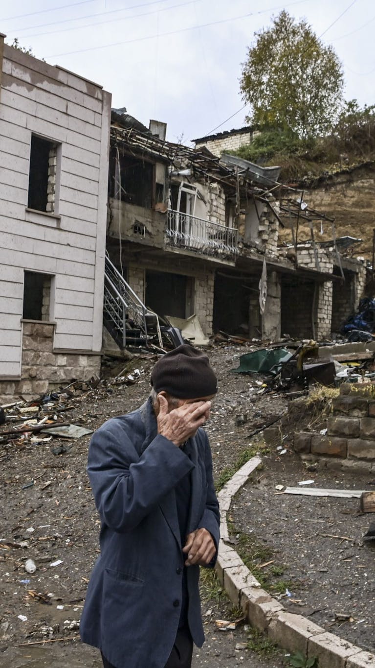 Een oude man loopt langs vernielde gebouwen in de hoofdstad nam Nagorno-Karabach. Armenië en Azerbeidzjan vechten om deze enclave, 6 oktober 2020