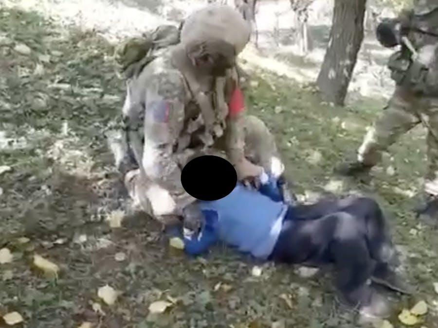 Een Azerbeidzjaanse militair duwt een oudere man tegen de grond . Even later wordt zijn keel doorgesneden.