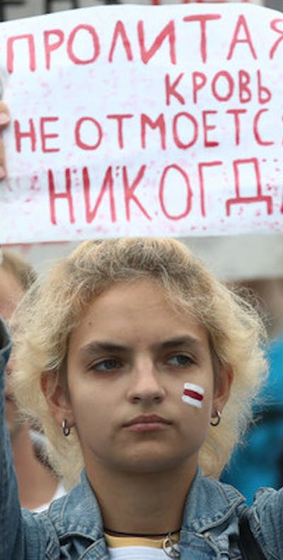 Een meisje houdt bij protesten in de hoofdstad van Wit-Rusland Minsk een papier omhoog met de tekst 'het vergoten bloed zal nooit verdwijnen'