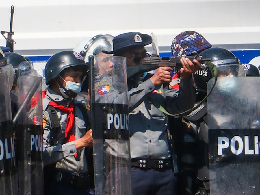 Tijdens protesten na de militaire staatsgreep in Myanmar op 12 februari 2021, richt een een politieagent zijn geweer op demonstranten