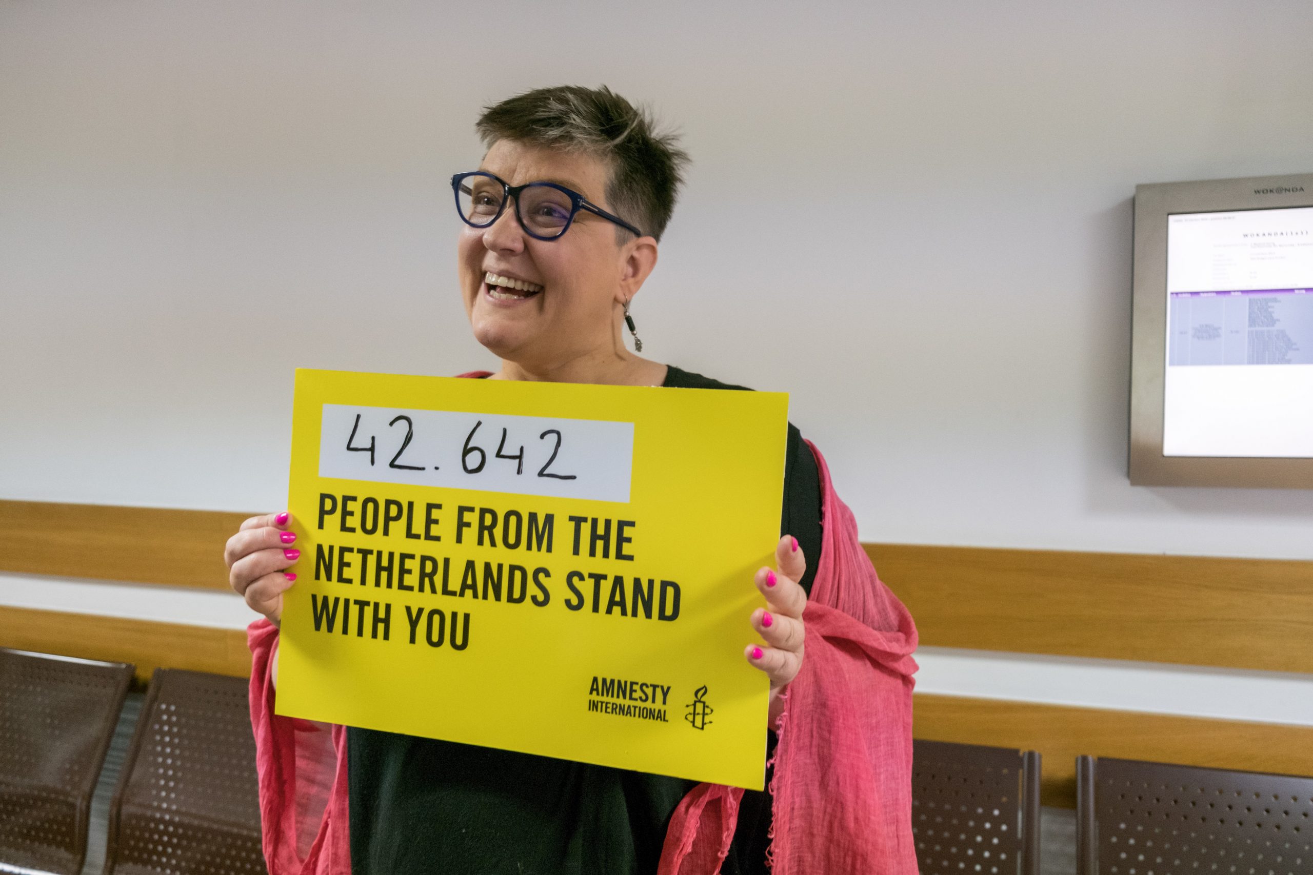 Elżbieta Podleśna in de rechtbank in Warschau in 2019, met een poster waarop het aantal steunbetuigingen uit Nederland staat vermeld. Ze werd met 13 andere vrouwen gehoord over hun rol in een demonstratie.