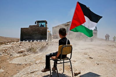 Palestijnse jongen kijkt toe hoe de Israëlische autoriteiten een school vernietigen in het dorpje Yatta op de Westelijke Jordaanoever. Israël maakt zich schuldig aan apartheid jegens Palestijnen.