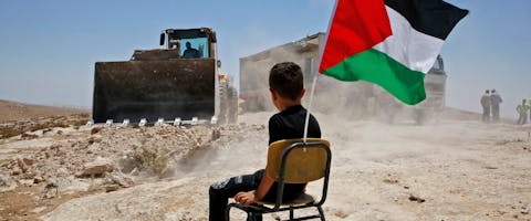 Palestijnse jongen kijkt toe hoe de Israëlische autoriteiten een school vernietigen in het dorpje Yatta op de Westelijke Jordaanoever. Israël maakt zich schuldig aan apartheid jegens Palestijnen.