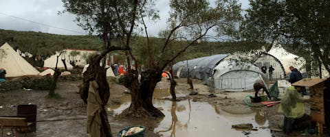 Vluchtelingen die per boot aankomen op Lesbos, Griekenland, vanuit Turkije. De vluchtelingen, voornamelijk uit Syrië en Afghanistan, werden ontvangen door vrijwilligers aan de noordkust van het eiland en begeleid naar het registratiekamp Moria. Van daaruit zouden de meesten via Athene naar andere EU-landen reizen om asiel aan te vragen. Op de foto is de registratiekamp te zien. Het heeft geregend en alles is nat geregend.