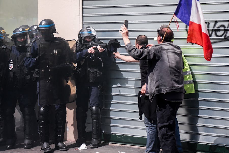 Een politieagent in Parijs richt zijn wapen waarmee rubberkogels worden afgevuurd op een demonstrant die tegen het regeringsbeleid in Frankrijk protesteert
