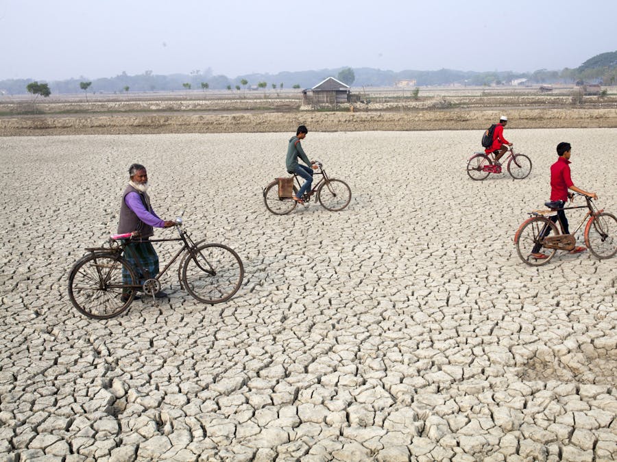 Dorpsbewoners op een opgedroogde rivierbedding in Satkhira, Bangladesh, waar klimaatverandering leidt tot zeespiegelstijging, erosie en andere milieuproblemen, met miljoenen mensen in gevaar.
