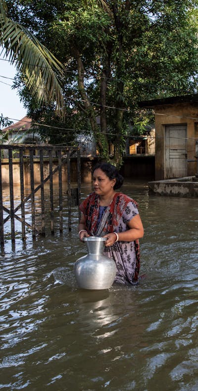 Een vrouw haalt water in een overstroomd gebied in Companiganj, Sylhet, Bangladesh op 22 juni 2022.