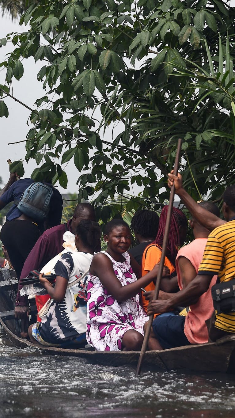 Reizigers zijn met een boot aan het overvaren, nadat overstromingen de Oost-West snelweg hebben onderbroken in Ahoada, Rivers State, Zuid-Nigeria.
