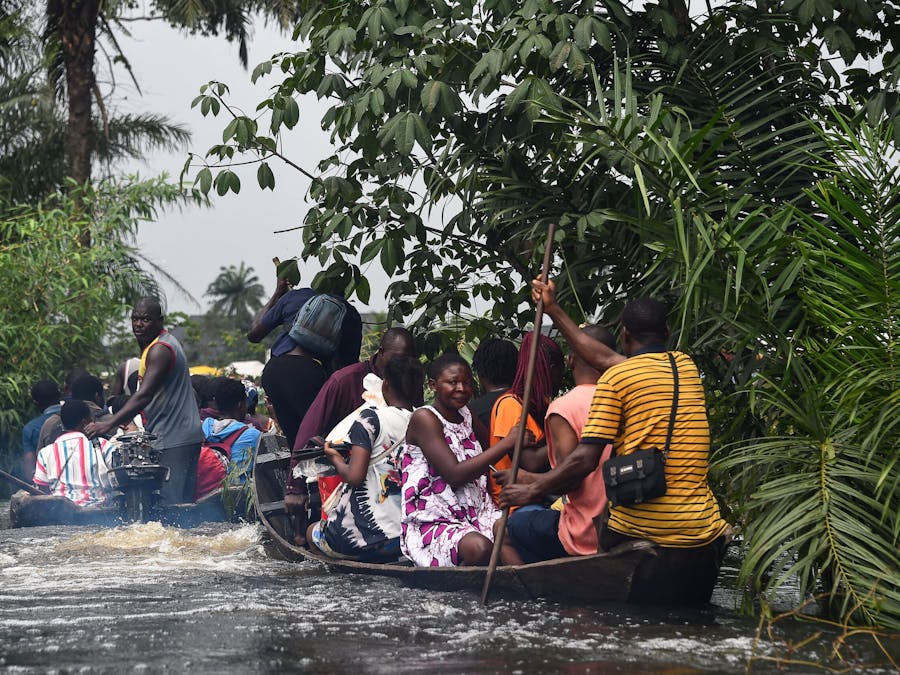 Reizigers zijn met een boot aan het overvaren, nadat overstromingen de Oost-West snelweg hebben onderbroken in Ahoada, Rivers State, Zuid-Nigeria.