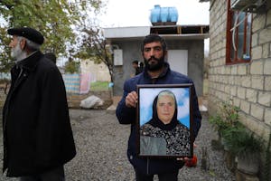 De zoon van Almaz Aliyeva houdt een foto vast van zijn moeder die op de binnenplaats van haar huis werd gedood door clustermunitie die op 27 oktober 2020 door Armeense troepen werd gelanceerd.