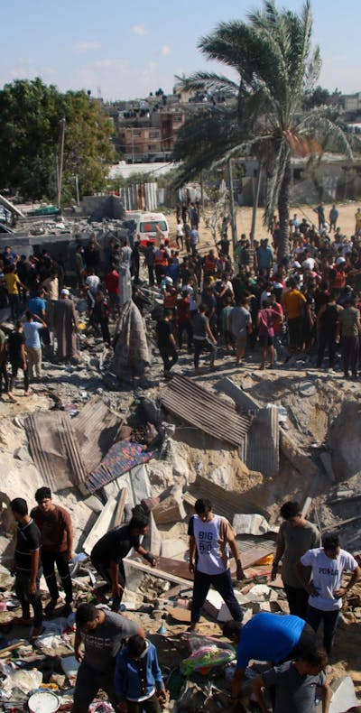 Palestijnse hulpdiensten en burgers zoeken naar slachtoffers bij verwoeste gebouwen in Zuid Gaza.
