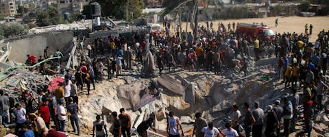 Palestijnse hulpdiensten en lokale burgers zoeken naar slachtoffers in gebouwen die zijn verwoest tijdens Israëlische luchtaanvallen in de zuidelijke Gazastrook op 19 oktober 2023 in Khan Yunis, Gaza