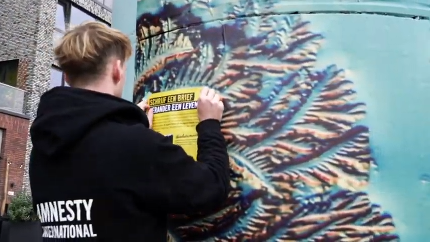 Amnesty vrijwilliger hangt een poster op om Write for Rights te promoten