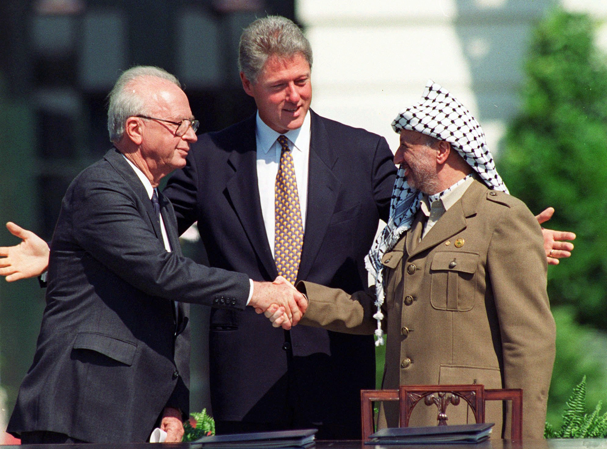 President Clinton met de Israëlische premier Yitzhak Rabin (l) en de Palestijnse leider Yasser Arafat tijdens de historische handdruk in 1993.
