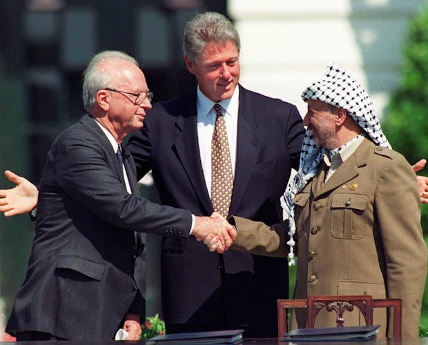 President Clinton met de Israëlische premier Yitzhak Rabin (l) en de Palestijnse leider Yasser Arafat tijdens de historische handdruk in 1993.