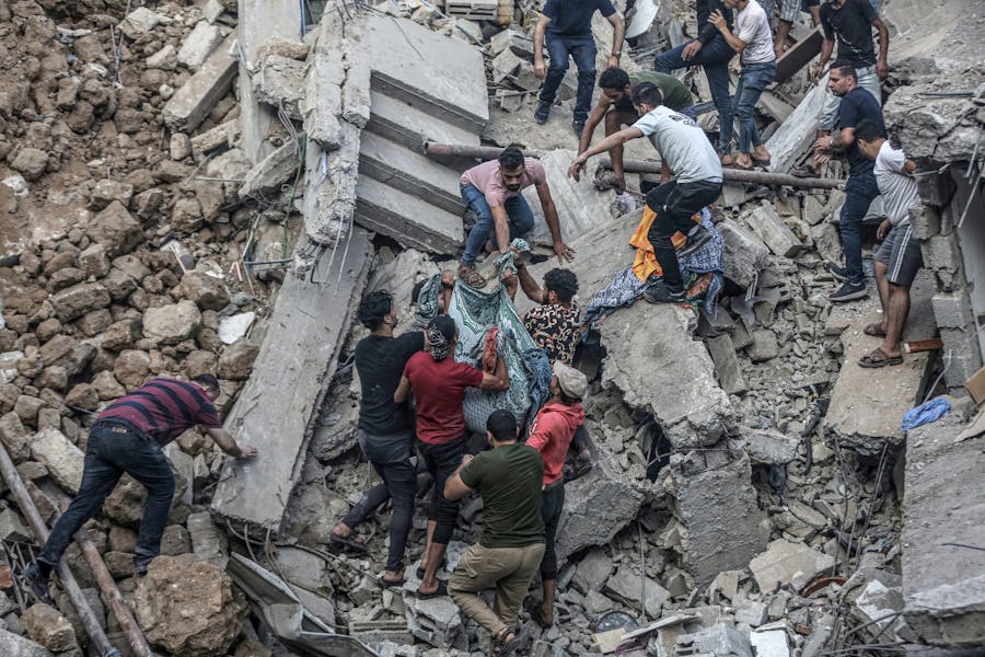 Mensen dragen een lijk dat uit het puin is gehaald na een Israëlische luchtaanval op de Grieks-orthodoxe Sint-Porfyruskerk in Gaza Stad op 20 oktober 2023. Minstens acht mensen zijn gedood bij de aanval op de kerk, die onderdak bood aan honderden Palestijnen.