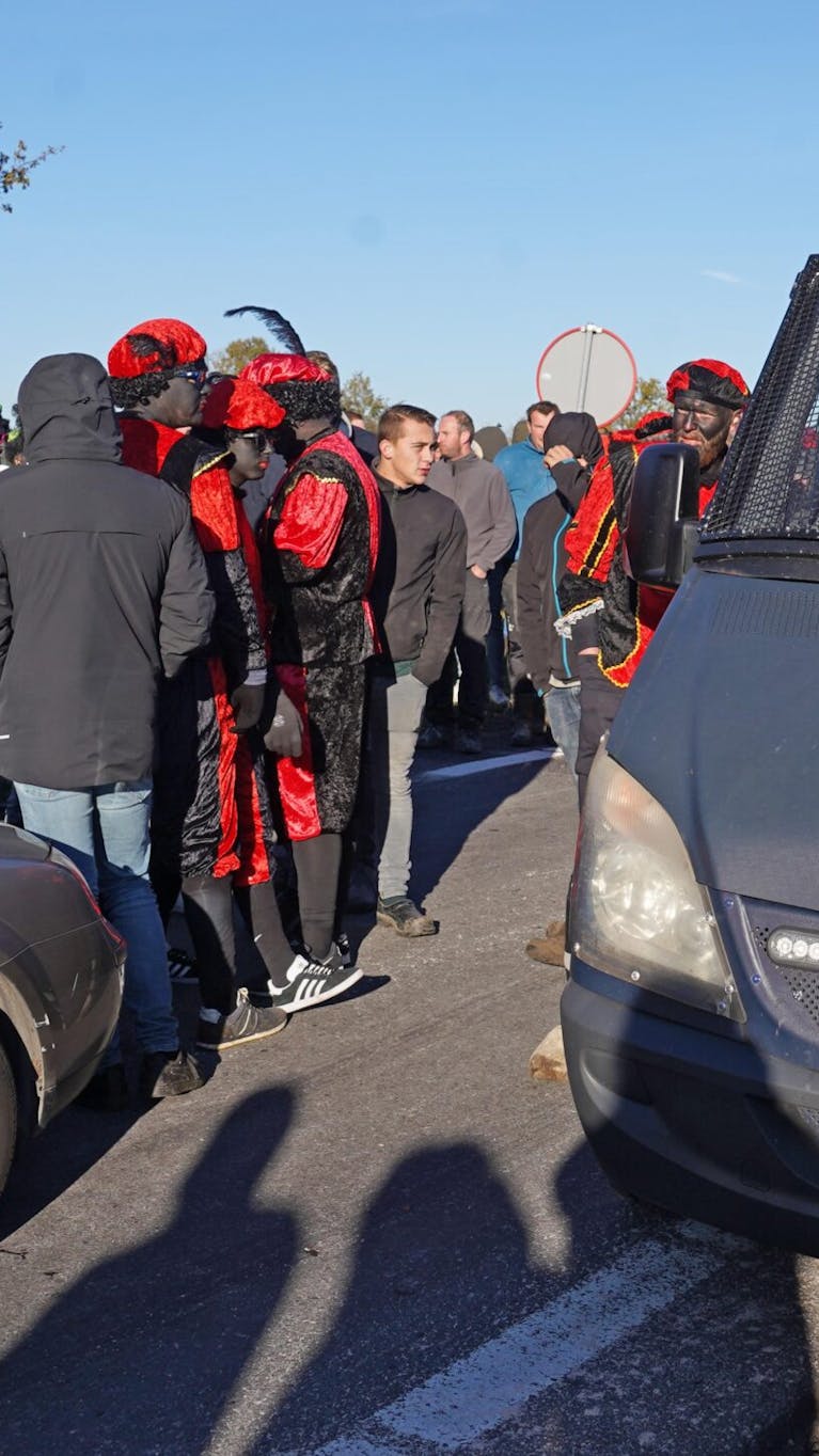 Deelnemers van Kick Out Zwarte Piet bij afrit A28 in Staphorst tegengehouden door menigte tijdens Sinterklaasintocht.