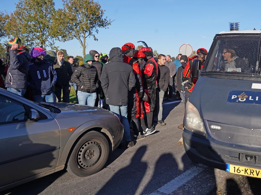 Deelnemers van Kick Out Zwarte Piet bij afrit A28 in Staphorst tegengehouden door menigte tijdens Sinterklaasintocht.